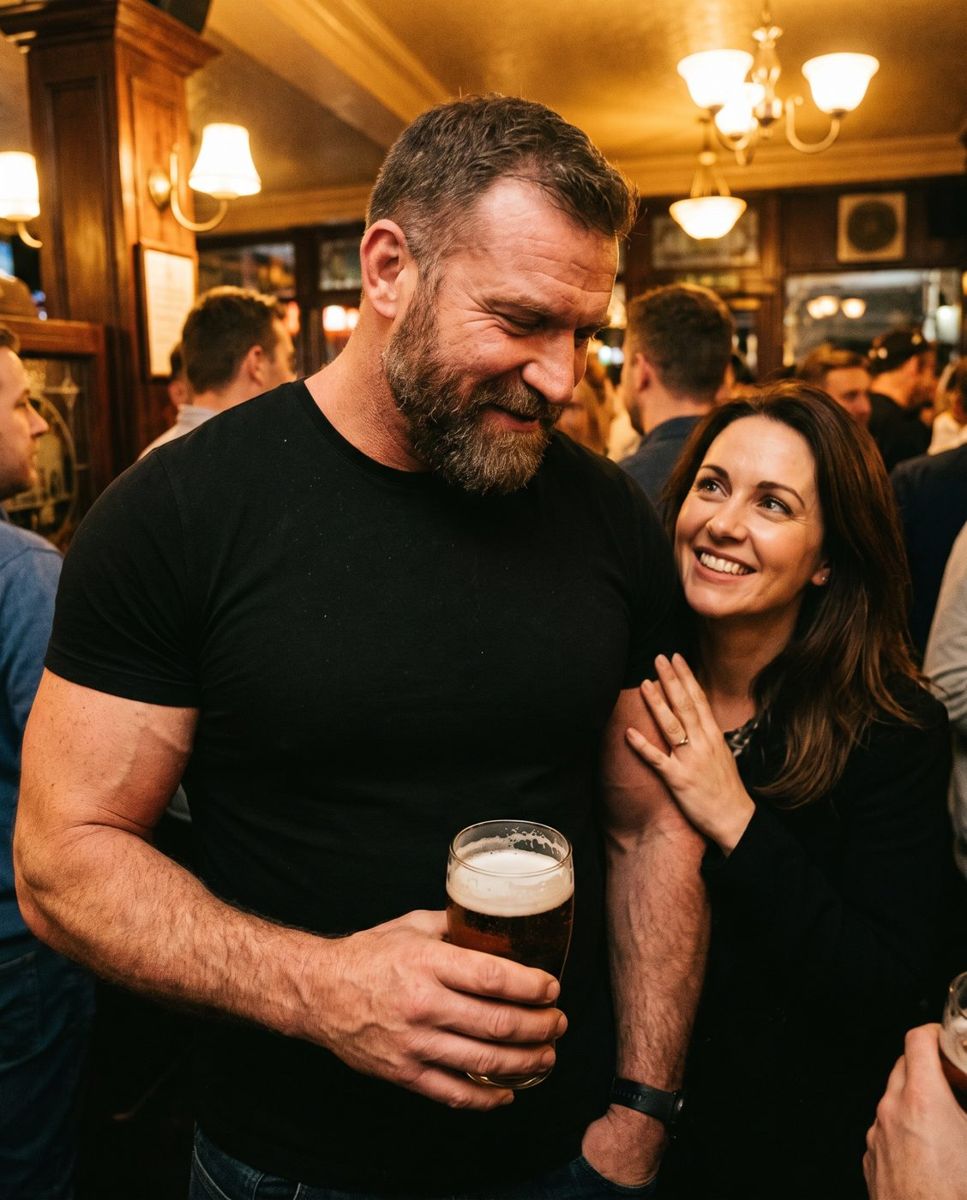 Jacked bearded man in his late 40s at a bar, a woman smiling with her hand on his arm
